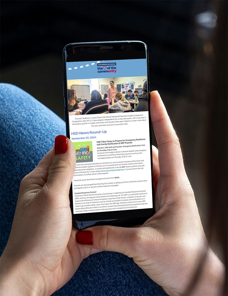 A woman holding a phone reading an email